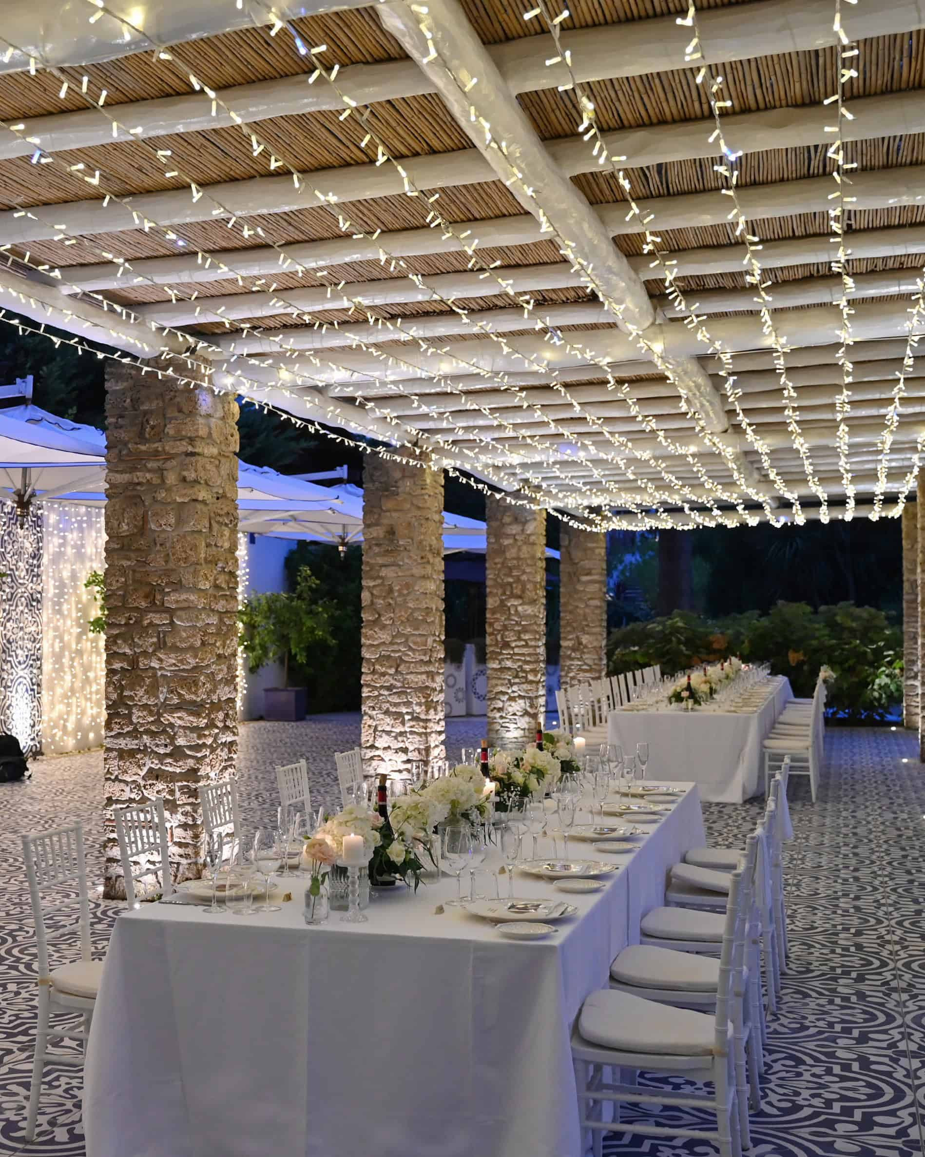 Long white table with flowers and decorated with lights from a wedding event at Esplanade Boutique Hotel